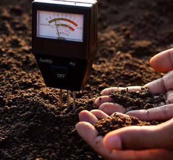 Soil tester in the soil with a woman's hands holding soil